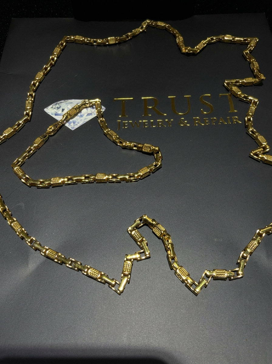 High-polish 21K gold chain and bracelet set on a dark branded surface